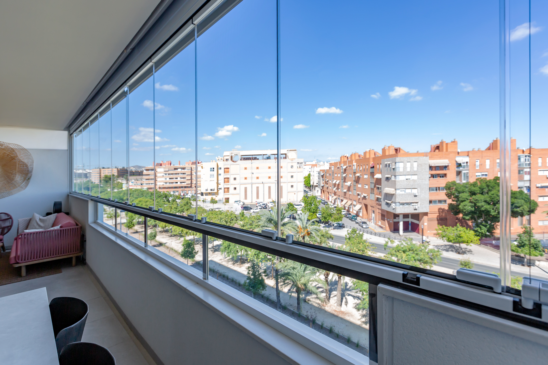 Wide angled photo of installed glass curtains on a balcony overlooking town.